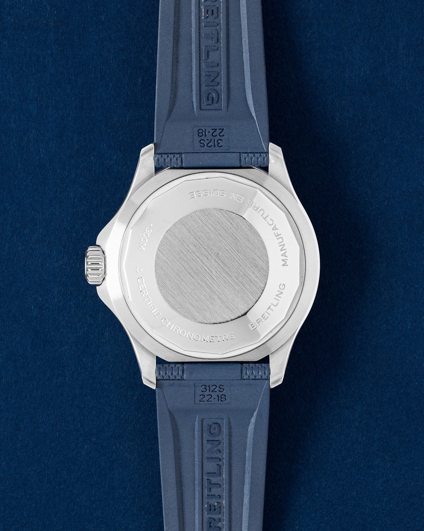 solid stainless steel screw-down caseback on a Breitling Superocean watch shown with an integrated blue rubber strap