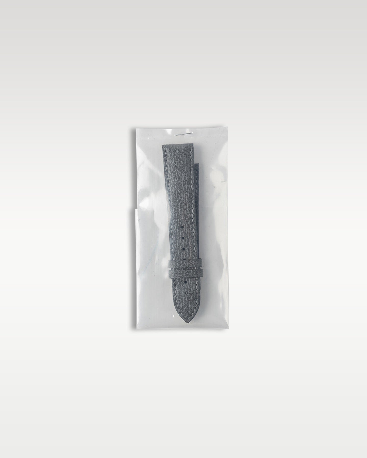Additional secondary grained grey leather strap factory sealed in original protective plastic packaging