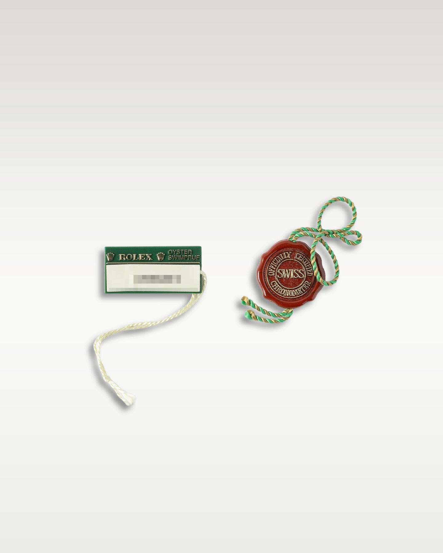 Official vintage red Rolex chronometer seal string tag alongside a green Swimpruf rectangular retail hang tag