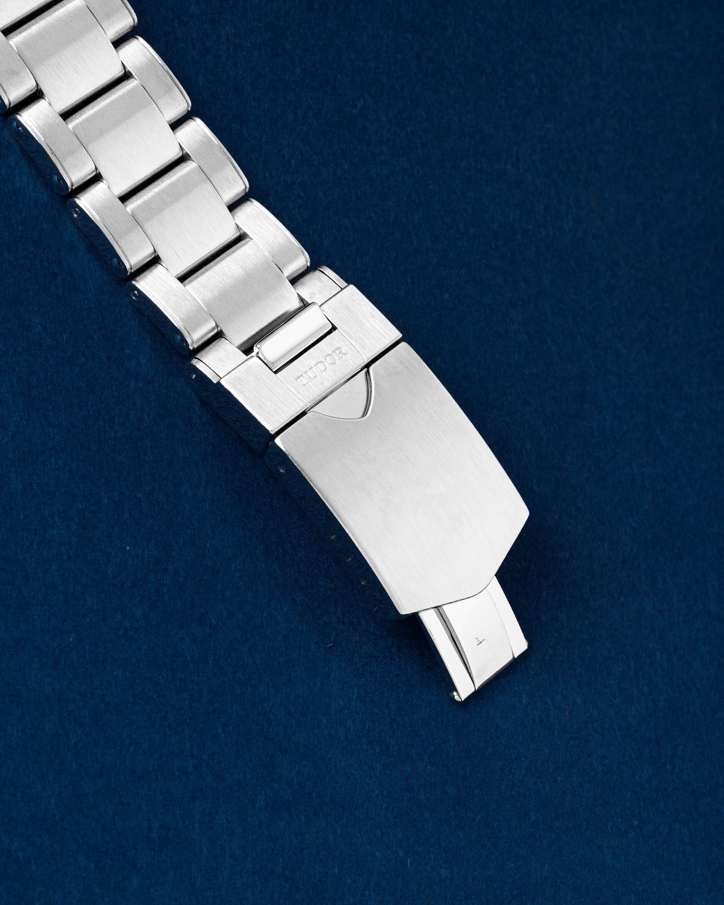 stainless steel safety clasp attached to a satin-brushed rivet-style sport watch bracelet