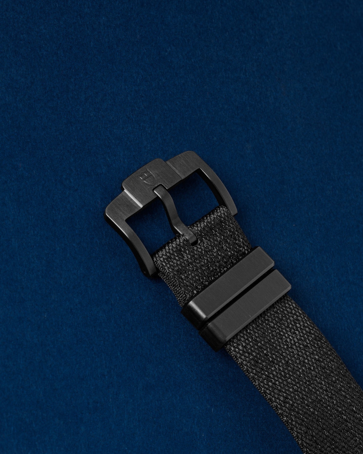black fabric hook-and-loop strap with a matte black titanium Ti ti-buckle closure on a Tudor Pelagos FXD watch