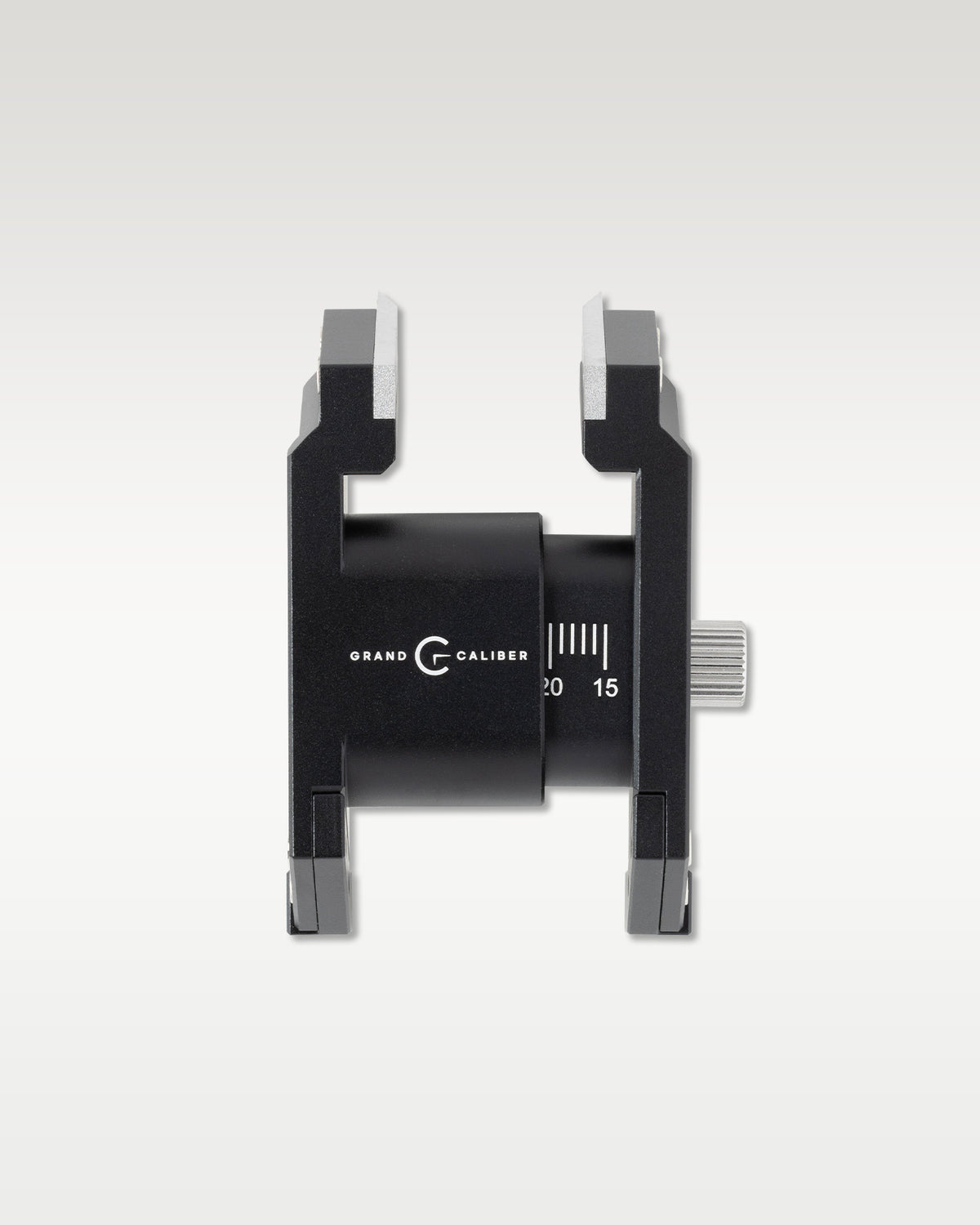 Overhead detail shot of a black Grand Caliber watchmaker casing tool showing dual adjustable clamp jaws and knurled side dial