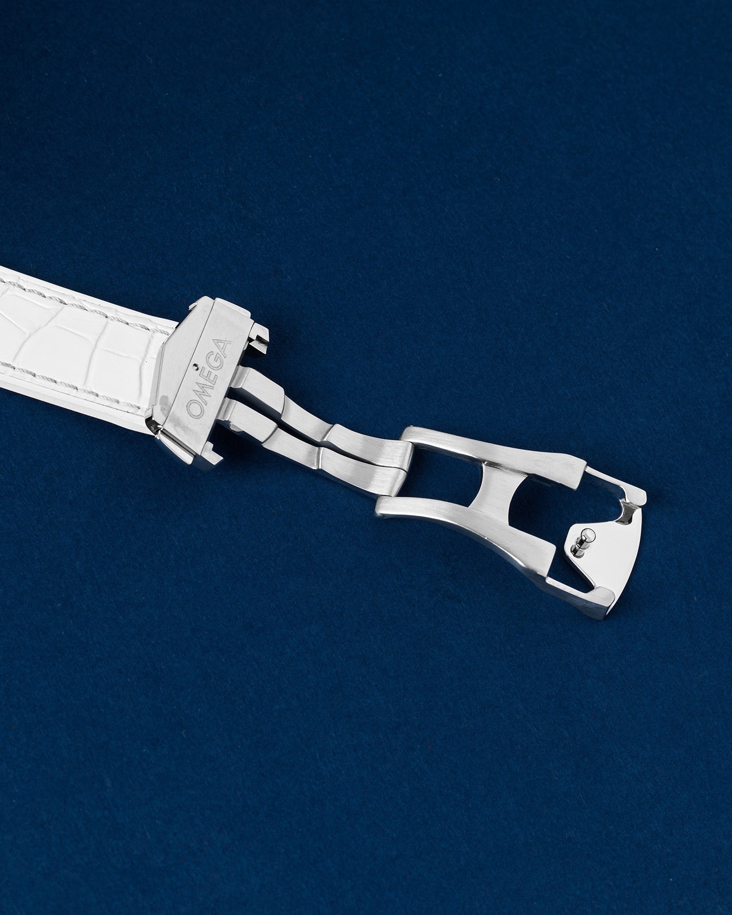 Detailed view of the open twin push-button stainless steel deployment buckle mechanism on a limited edition Omega watch strap