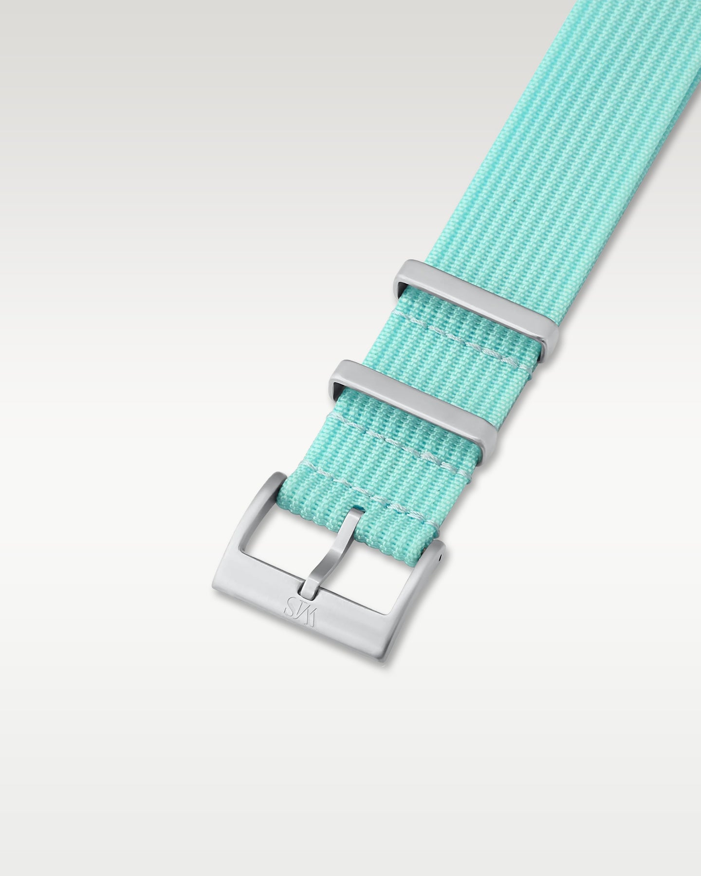 Angled detail shot of a lagoon blue nylon watch band showing its pre-installed brushed silver pin buckle