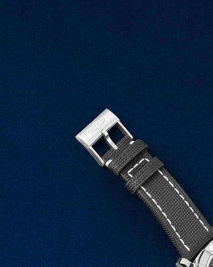 Close-up view of the brushed stainless steel tang buckle clasp on a black textile-leather Breitling strap