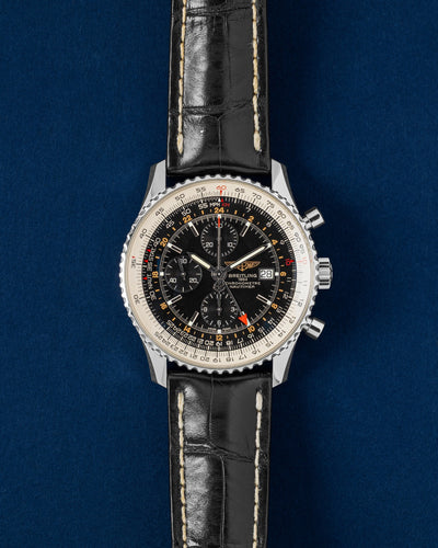 A preowned 46mm Breitling Navitimer World GMT Chronograph reference A24322 featuring an ebony black dial, silver sunken sub-registers, and an independent red dual-time zone hand at Grand Caliber in Dallas