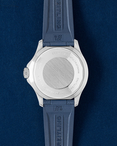 solid stainless steel screw-down caseback on a Breitling Superocean watch shown with an integrated blue rubber strap