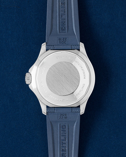 solid stainless steel screw-down caseback on a Breitling Superocean watch shown with an integrated blue rubber strap