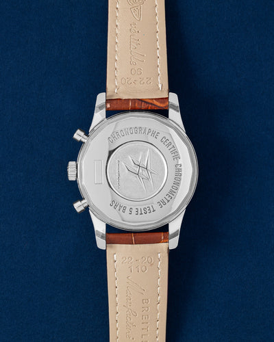 The reverse layout of the polished steel watch case focusing on the solid screw-down back plate featuring Breitling's classic stylized wing logo and technical calibration scales