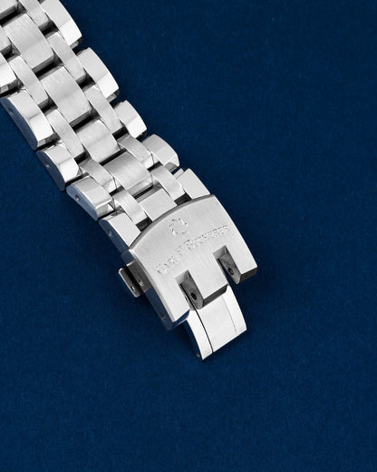 An angled view of the wide articulated multi-row steel link band focusing on the robust folding safety deployant buckle detailed with the Carl F. Bucherer name crest