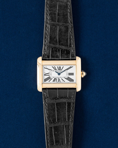 A preowned 18k yellow gold Cartier Tank Divan reference W6300356 showcasing its unique horizontally stretched rectangular silhouette, silver guilloche dial, and black Roman numerals at Grand Caliber in Dallas