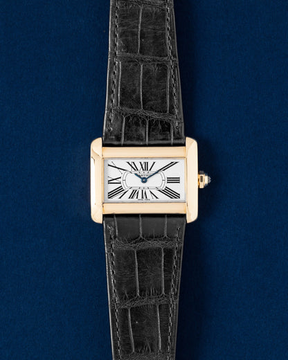 A preowned 18k yellow gold Cartier Tank Divan reference W6300356 showcasing its unique horizontally stretched rectangular silhouette, silver guilloche dial, and black Roman numerals at Grand Caliber in Dallas