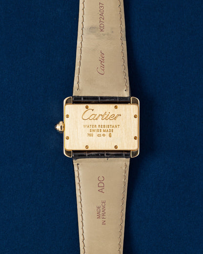 The reverse profile of the wide rectangular 18k gold watch head highlighting the solid satin-brushed gold caseback secured by eight pristine assembly screws over a blue background
