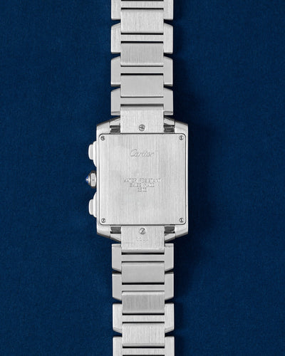 Solid rectangular stainless steel screw-down caseback displaying serial numbers and signature Cartier branding script