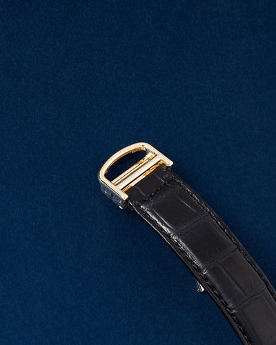 Close-up profile view of the black alligator strap highlighting the solid 18k yellow gold Cartier deployant buckle clasp closure