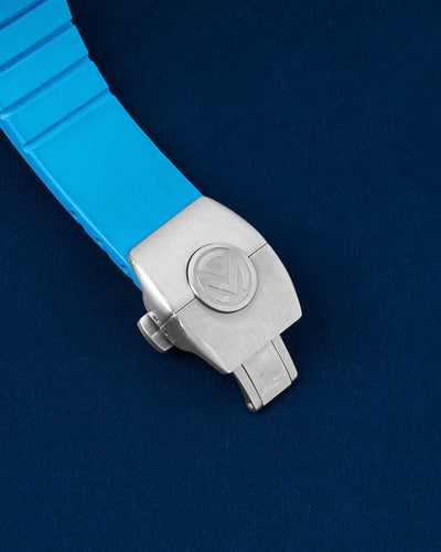 An angled portrait of the custom integrated blue rubber marine band focusing on the secure satin-brushed folding safety buckle catch stamped with the Franck Muller shield crest