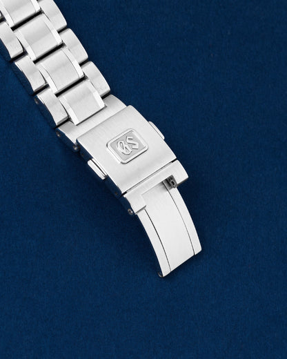 An angled view of the multi-link satin-finished metal bracelet focusing on the flush-fitted folding deployment lock decorated with a crisp debossed GS emblem