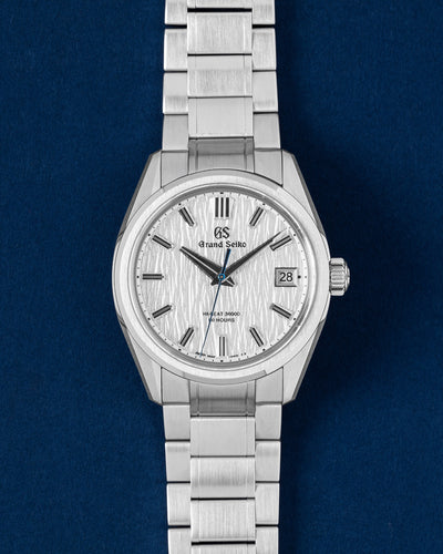 A pre-owned 2024 Grand Seiko Evolution 9 SLGH005 displaying its signature silver-white textured Shirakaba linear dial and heat-blued sweeping seconds hand at Grand Caliber in Dallas