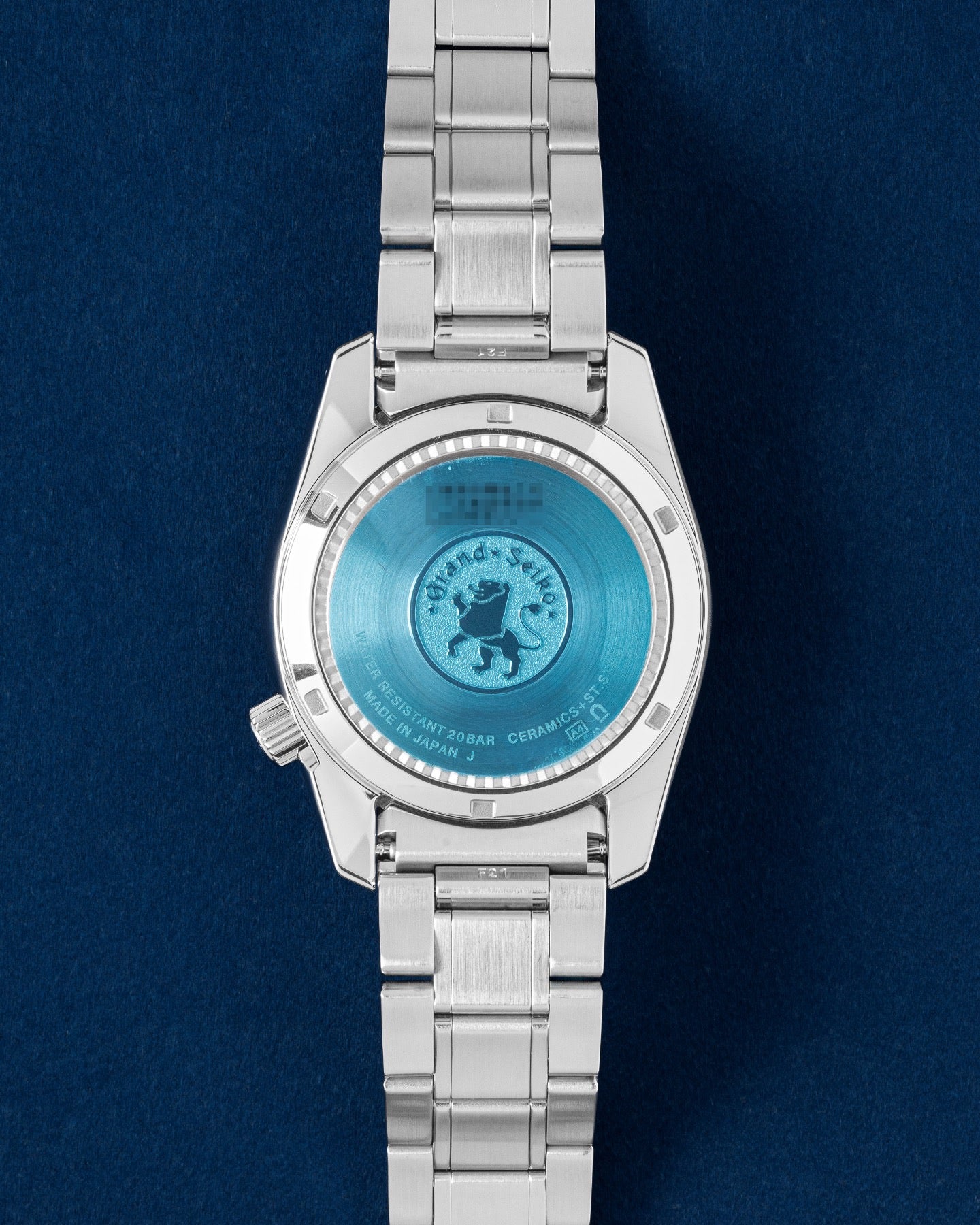 The solid stainless steel screw-down caseback of a Grand Seiko watch showing the embossed brand lion emblem