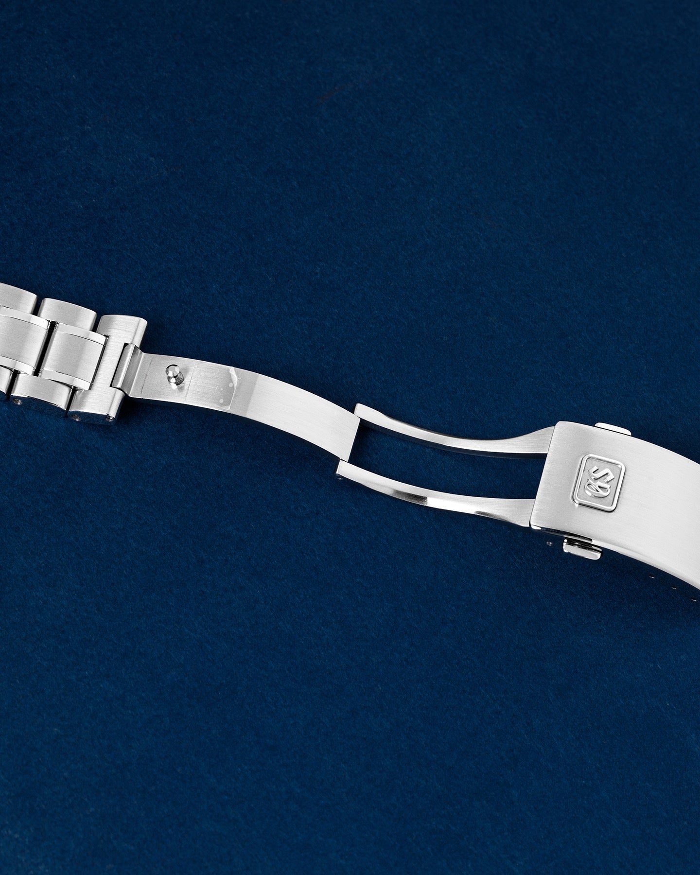 Open stainless steel deployant clasp mechanism on a Grand Seiko sport watch link bracelet
