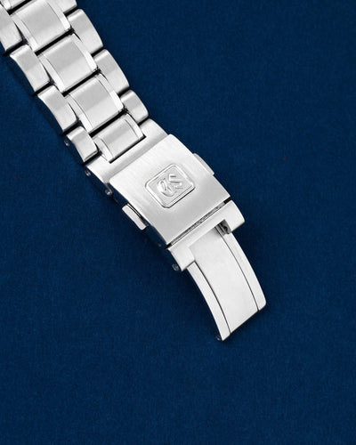 Close-up of the stainless steel three-link bracelet highlighting the brushed folding clasp with the raised Grand Seiko GS logo emblem