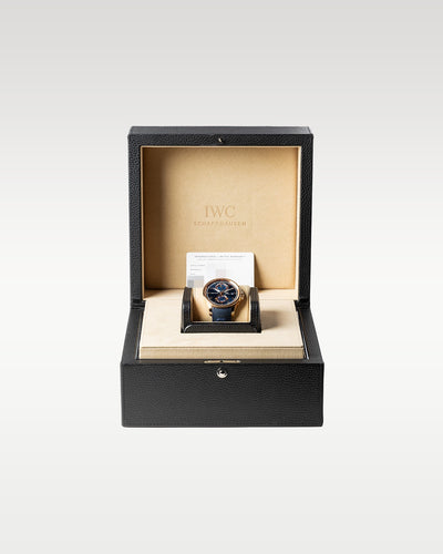 An open matte black rectangular IWC luxury watch box displaying the 18k gold Yacht Club Moon Tide watch nested securely inside