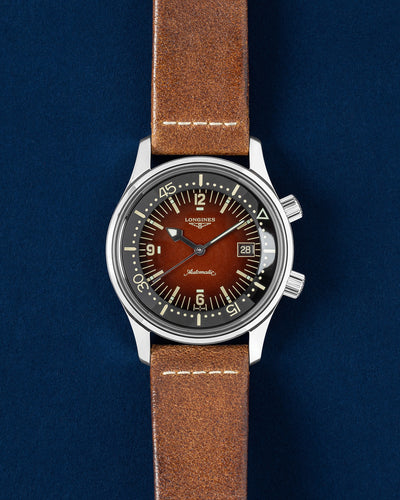 Longines Legend Diver 42mm L3.774.4 compressor watch with a tobacco brown gradient dial and brown leather strap on a navy blue studio background