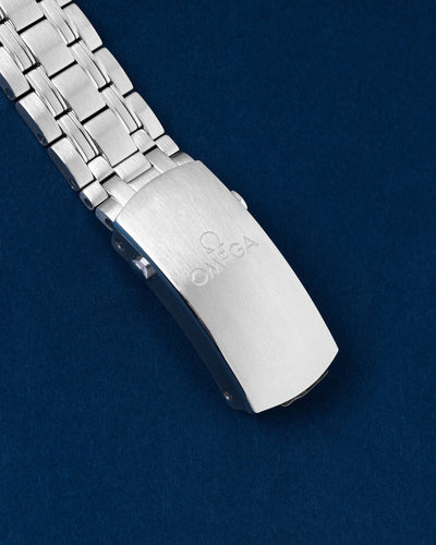 An angled view of the robust five-row stainless steel metal link band focusing on the satin-brushed fold-over push-button deployment clasp engraved with the Omega brand name