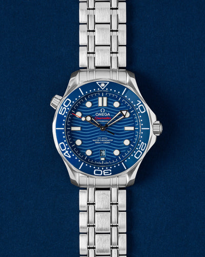 A preowned 2023 Omega Seamaster Diver 300M reference 210.30.42.20.03.001 showing its blue ceramic wave dial, skeleton hands, and iconic blue ceramic timing bezel insert at Grand Caliber in Dallas