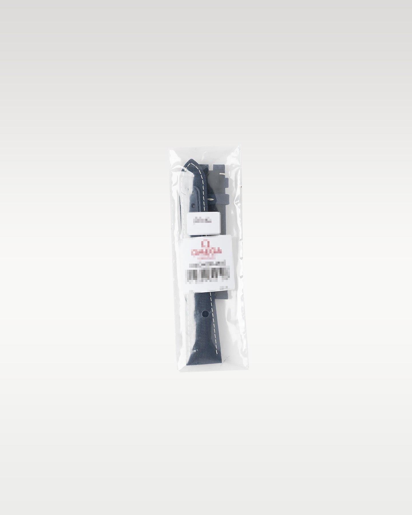 An authentic black textured rubber or fabric secondary watch strap sealed inside official protective transparent factory plastic packaging