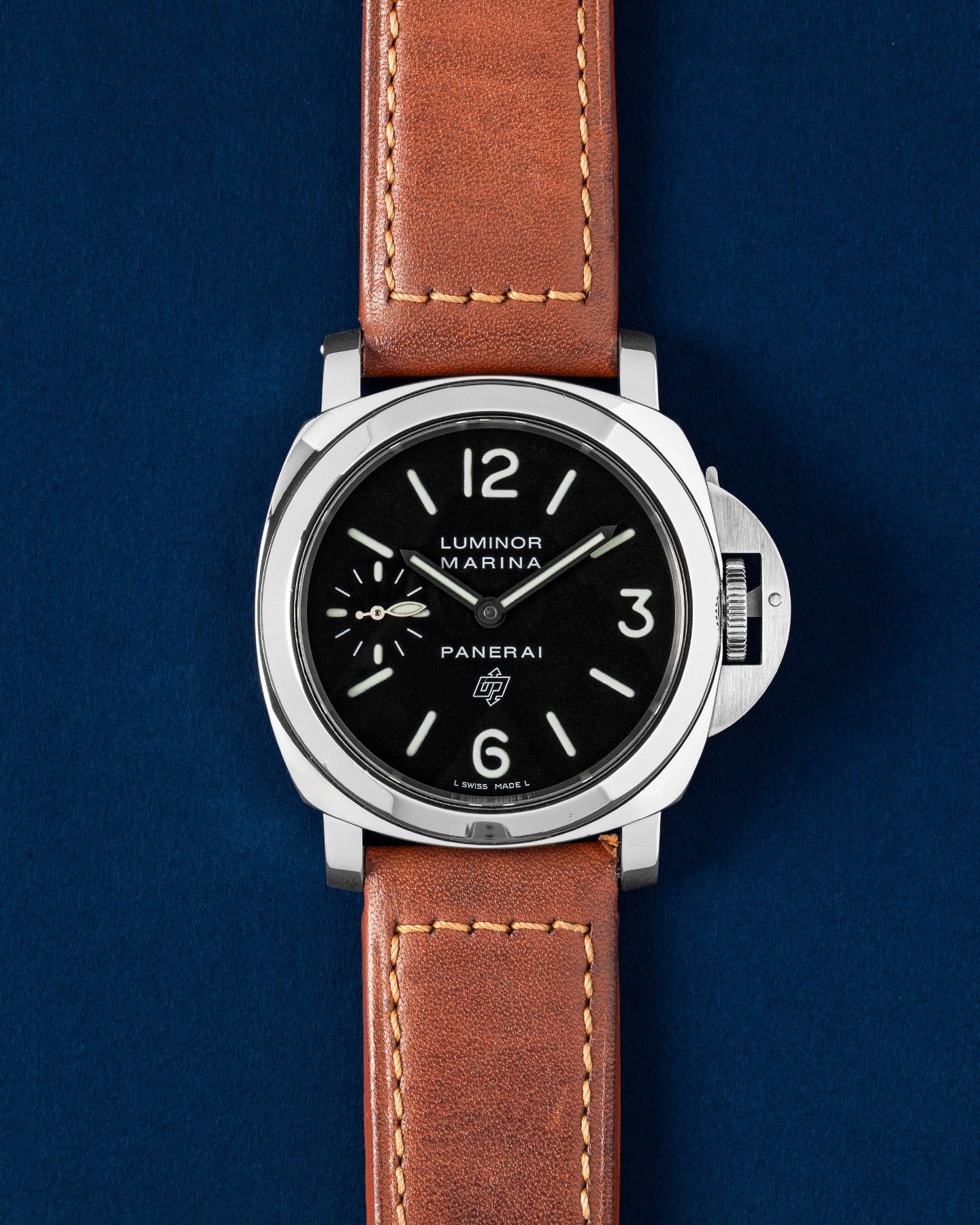 A preowned 2005 Panerai Luminor Marina Logo PAM 00005 displaying its original black dial luminescent hands and signature oversized crown guard mechanism with a brown leather strap at Grand Caliber in Dallas, Texas