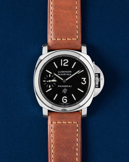 A preowned 2005 Panerai Luminor Marina Logo PAM 00005 displaying its original black dial luminescent hands and signature oversized crown guard mechanism with a brown leather strap at Grand Caliber in Dallas, Texas