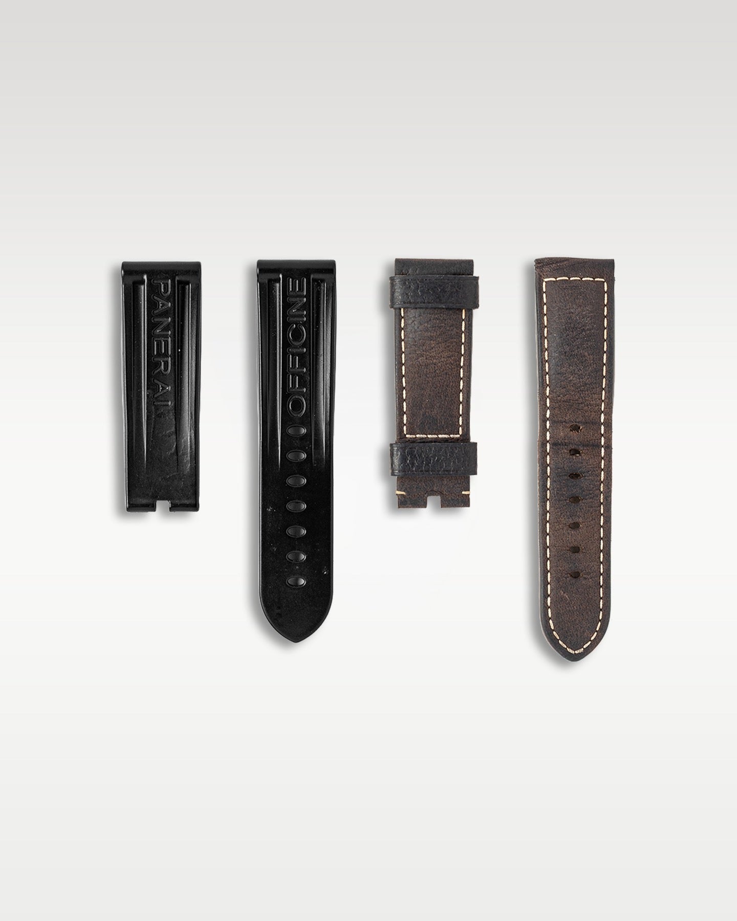 A flat lay view of the extra accessory straps including black rubber and dark brown leather variants accompanying the Panerai Luminor Marina Logo PAM 00005 at Grand Caliber in Dallas, Texas