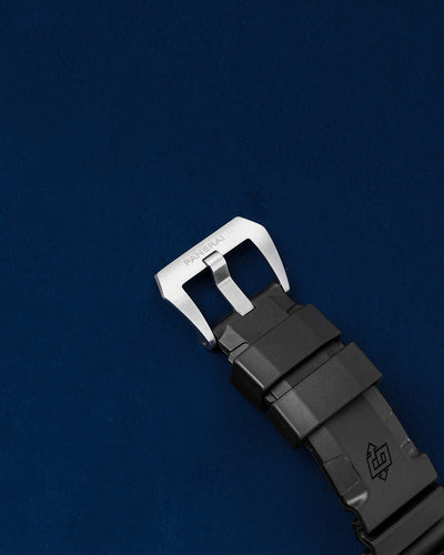 Close-up view of the brushed stainless steel trapezoid tang buckle clasp on a black Panerai logo rubber strap