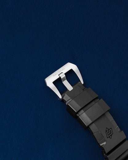 Close-up view of the brushed stainless steel trapezoid tang buckle clasp on a black Panerai logo rubber strap