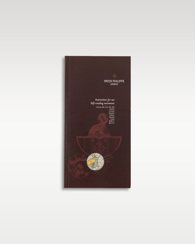 The clean front cover of the traditional thick dark brown booklet containing global user operating instructions for self winding movements accompanying the Patek Philippe Nautilus 5711 at Grand Caliber in Dallas, Texas
