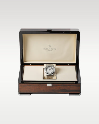 The complete retail collector presentation layout showing the white dial Patek Philippe Nautilus 5711 timepiece resting safely inside its inner polished dark wood luxury display chest on a beige cushion at Grand Caliber in Dallas, Texas