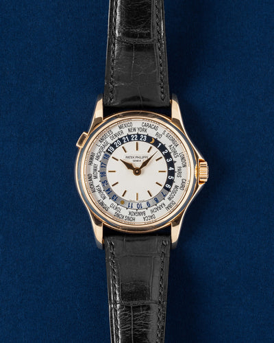 37mm 18k rose gold Patek Philippe World Time 5110R-001 watch featuring a silver guilloche dial and black alligator strap resting on a navy blue background