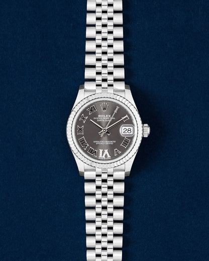Brand new 2026 Rolex Datejust 31 278274 watch with a slate gray Roman numeral dial and 18k white gold fluted bezel on a navy blue studio background