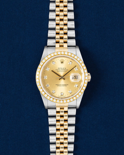 frontal studio portrait of a two tone Rolex Datejust 36 16203 featuring a champagne diamond dial, custom diamond-set gold bezel and Jubilee bracelet on a navy blue background