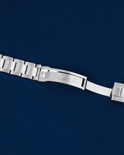 flat top-down view of the internal folding clasp blades and hinge mechanism of a stainless steel Rolex Oyster bracelet open over a navy background