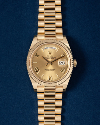 A preowned 2022 Rolex Day-Date 40 reference 228238 in solid 18k yellow gold featuring a champagne sunburst dial with faceted gold Roman numeral indices at Grand Caliber in Dallas