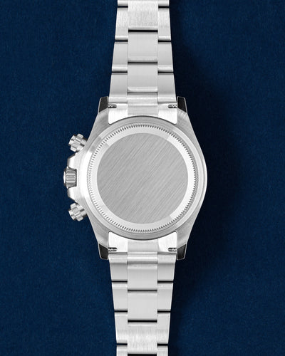 The solid Oystersteel caseback profile view of a white dial Rolex Daytona 126500LN showcasing the screw-down chronograph pushers and crown