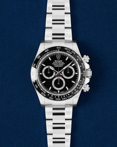 2024 Rolex Cosmograph Daytona 126500LN watch featuring a black dial black Cerachrom tachymeter bezel and stainless steel Oyster bracelet on a navy blue studio background