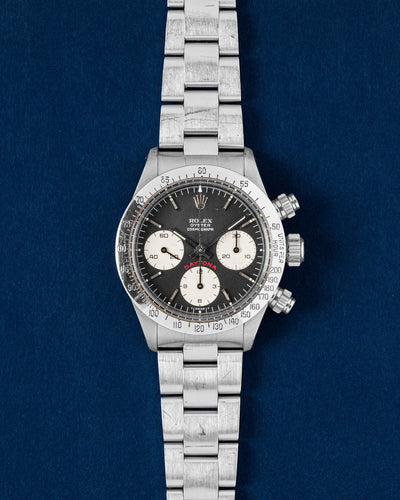 1979 vintage Rolex Cosmograph Daytona 6265 featuring a matte black 'Big Red' dial and stainless steel tachymeter bezel on a navy blue studio background
