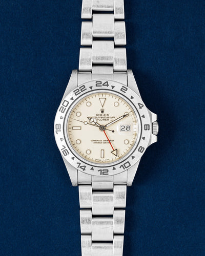 1986 neo-vintage Rolex Explorer II 16550 featuring a rare transitional cream panna dial and brushed steel bezel on a navy blue studio background