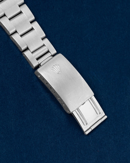 An angled portrait of the satin-finished three-piece link Oyster bracelet focusing on the secure closure of the vintage period-correct stamped single-lock folding buckle detailed with the Rolex crown emblem