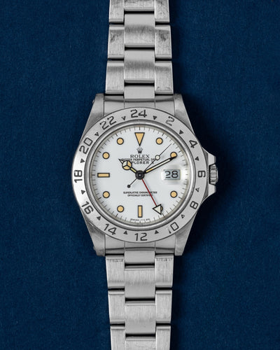 A vintage 1991 Rolex Explorer II reference 16570 featuring its iconic polar white dial, contrasting black-trimmed creamy tritium hour markers, and red GMT hand at Grand Caliber in Dallas