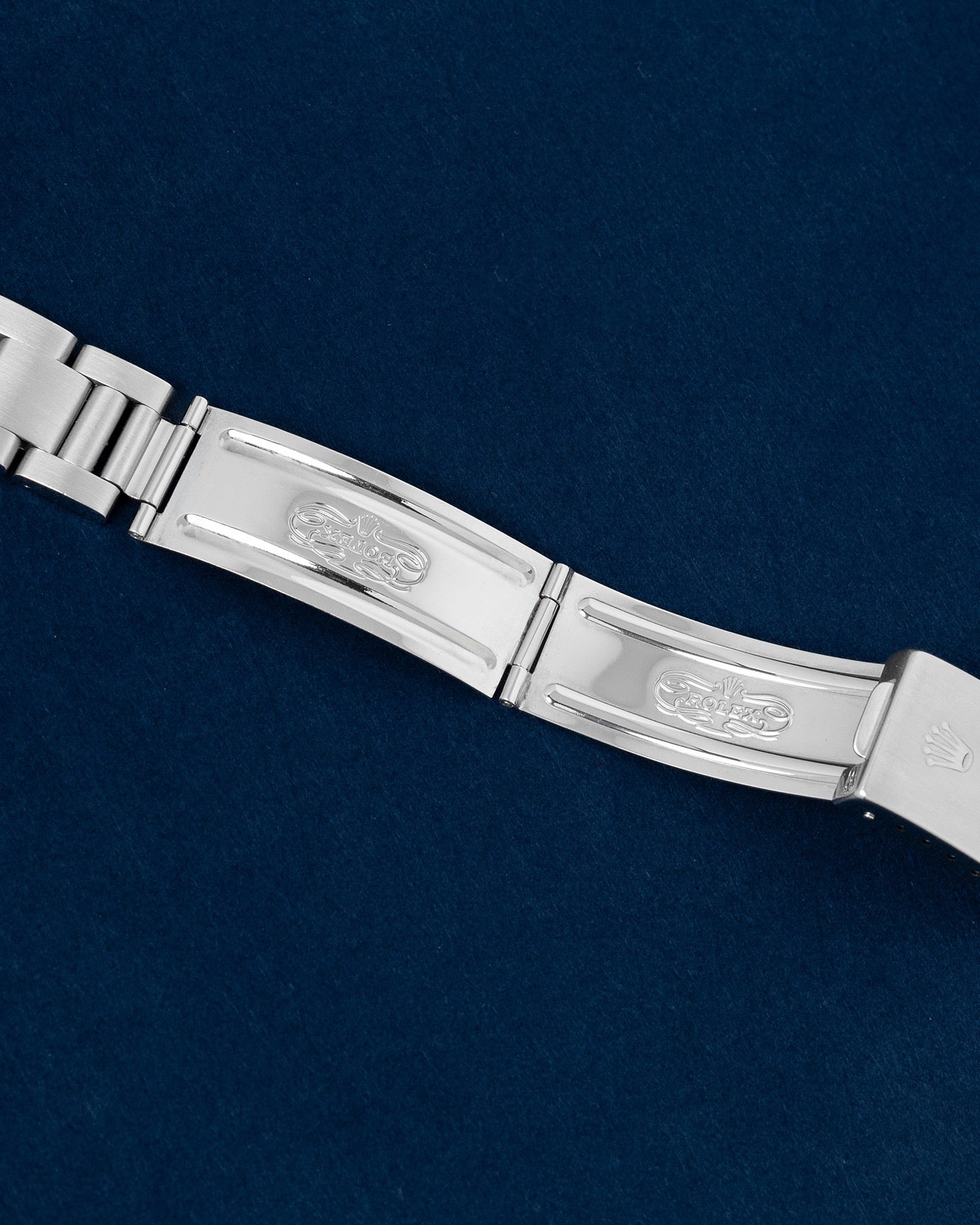 flat lay shot of the interior folding blades of the open stainless steel Oyster bracelet showing the official vintage Rolex registered design factory stamps