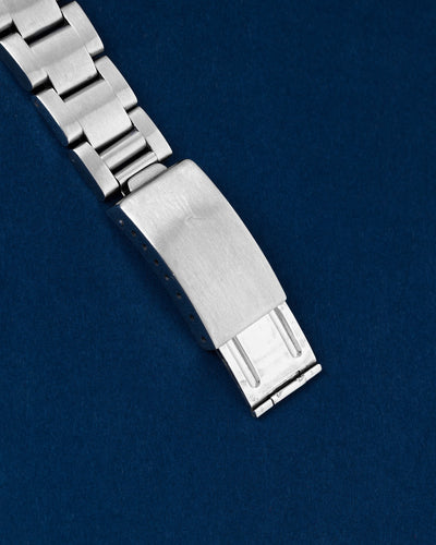 An angled view of the period-correct stainless steel three-link Oyster bracelet focusing on the secure closure of the vintage stamped single-lock folding clasp detailed with a clean Rolex coronet